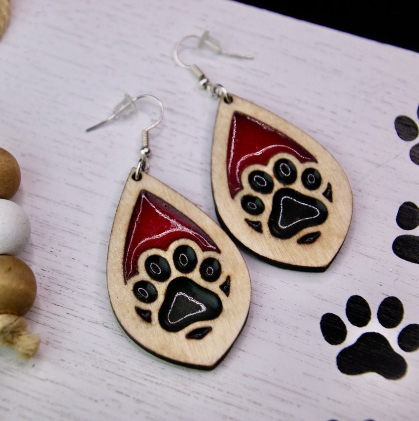Tear drop dangle earring with a single paw print with pink and black resin, approximately 2.5 inches. They are laser cut, lightweight birchwood dangle earring that can be worn easily all day. Great gift for mom or any pet lover.