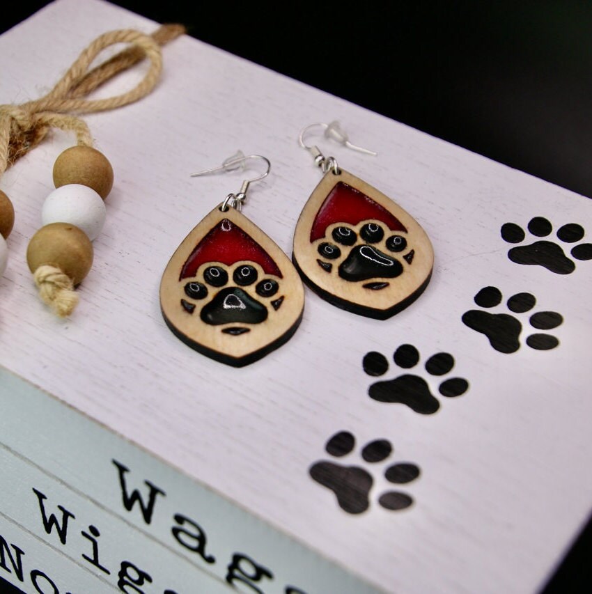 Tear drop dangle earring with a single paw print with pink and black resin, approximately 2.5 inches. They are laser cut, lightweight birchwood dangle earring that can be worn easily all day. Great gift for mom or any pet lover.